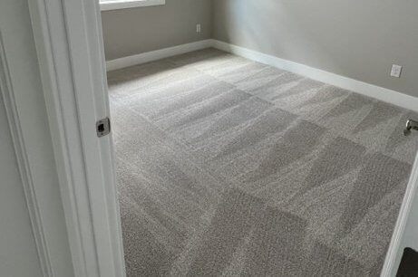 Freshly cleaned carpet with even vacuum lines in an empty bedroom