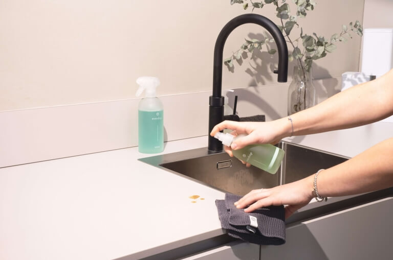 Cleaner wiping down a kitchen sink during a regular cleaning
